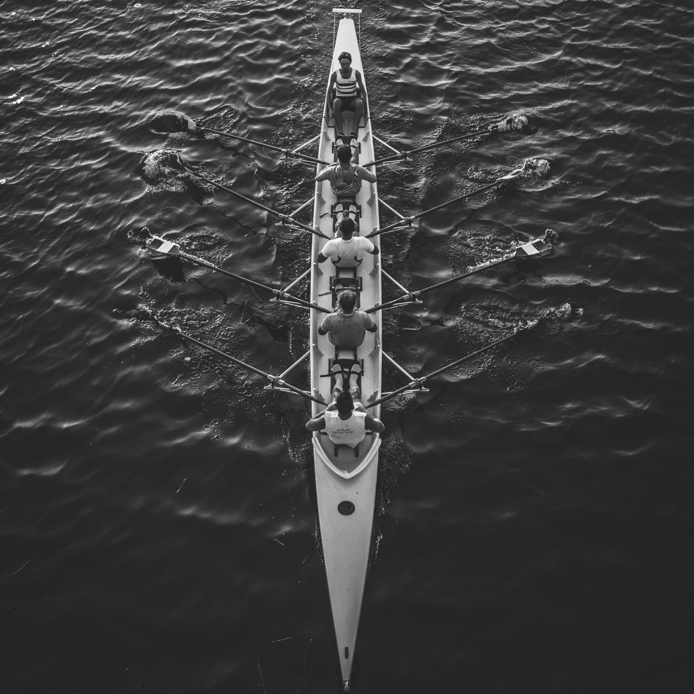 Vue aérienne d'un équipage d'aviron : chaque rameur tire son propre aviron, tous dans le même mouvement.